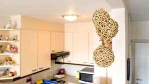 A kitchen with white cabinets, a microwave, and a hanging wicker ball decoration. - Simplistic Apartment in Blankenberghe near Belgium Pier (Blankenberghe)