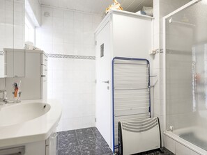 Une salle de bain avec un lavabo blanc, un miroir, un porte-serviettes et un espace douche.
