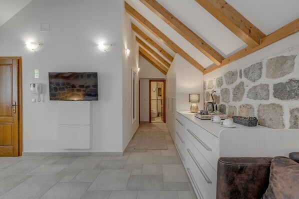 Una cocina moderna con pared de piedra, vigas de madera y televisor de pantalla plana.