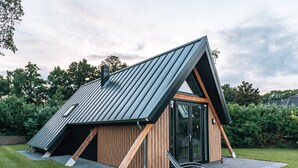 Ein modernes Haus mit Satteldach, Holzfassade und Glastür.