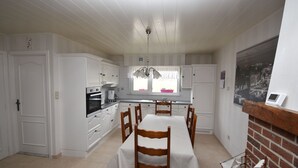 A kitchen with white cabinets, a dining table with chairs, a built-in oven, and a window with a view of the city.
