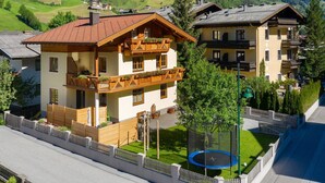 Ein Chalet mit Balkon, einem Trampolin im Hof und einem Blick auf die Berge.
