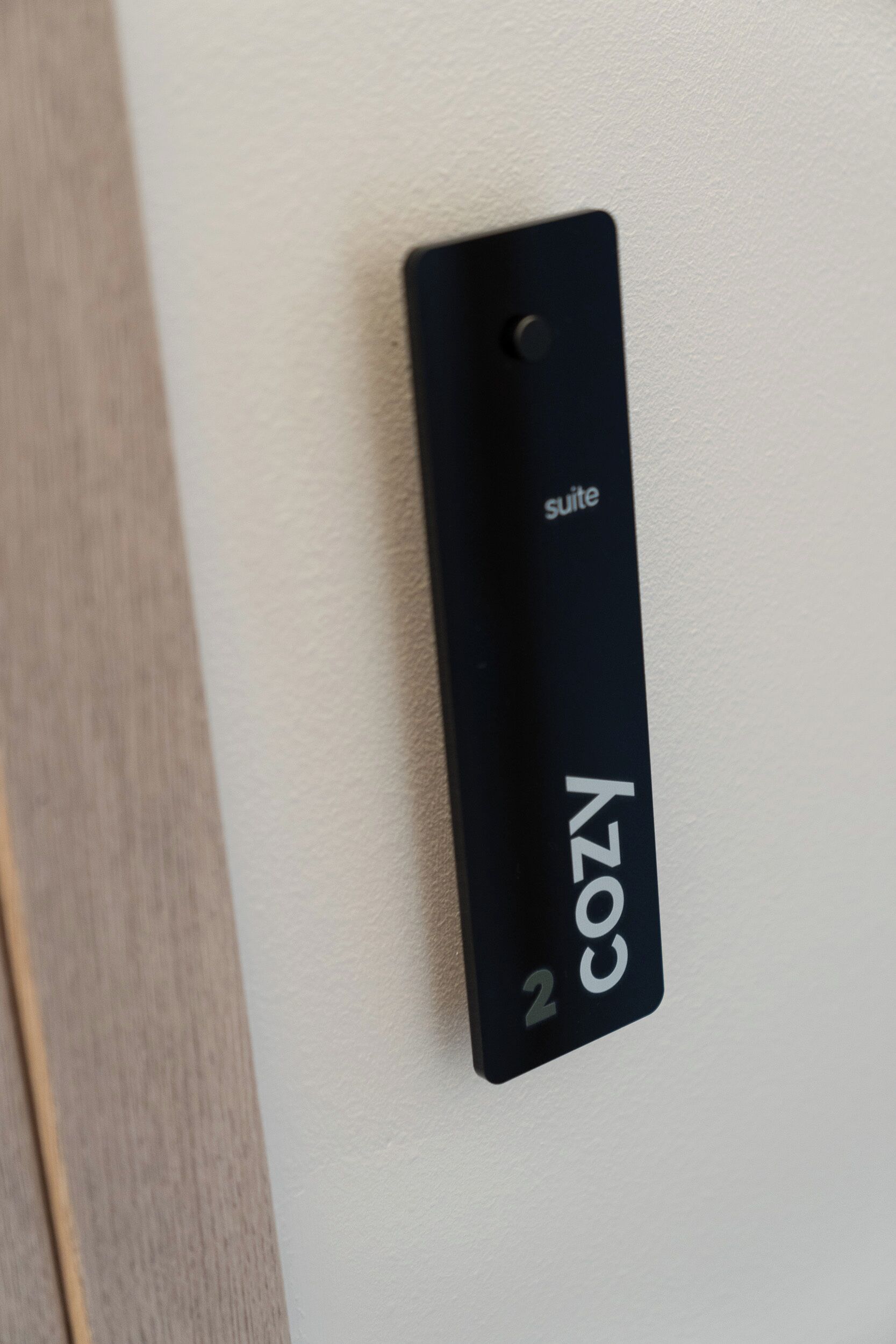 A black sign with the text "suite 2" and "COZY" on a white wall.