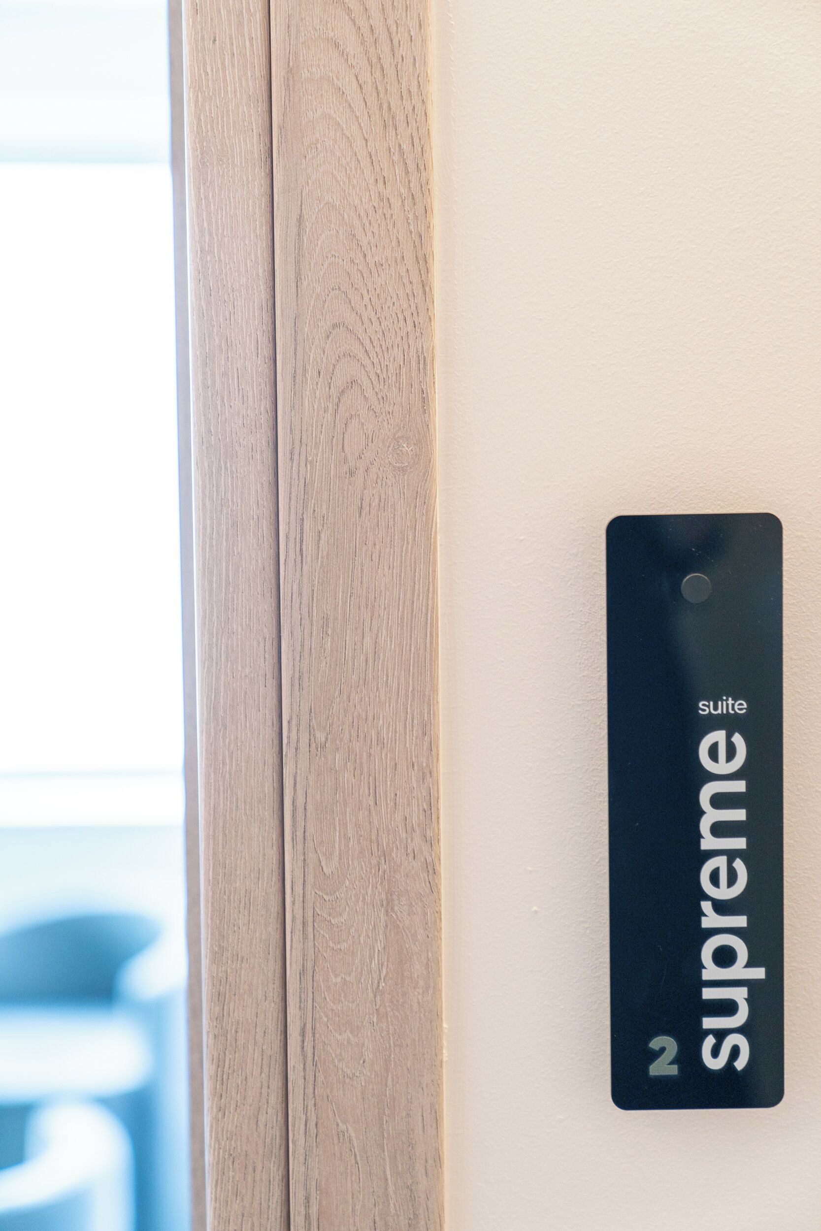 Een deur met een houten frame en een zwart bordje met de tekst 'suite 2 supreme'.