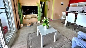 A living room with a TV, plants, a small table, and a kitchen area with a microwave. - Villa 19 Julia apartment with sea view and 3 bedrooms (Tribunj)