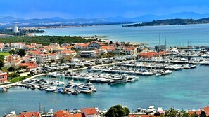 A marina with numerous boats docked, surrounded by residential buildings with red roofs, and a clear view of the sea and distant mountains. - Villa 19 Julia apartment with sea view and 3 bedrooms (Tribunj)