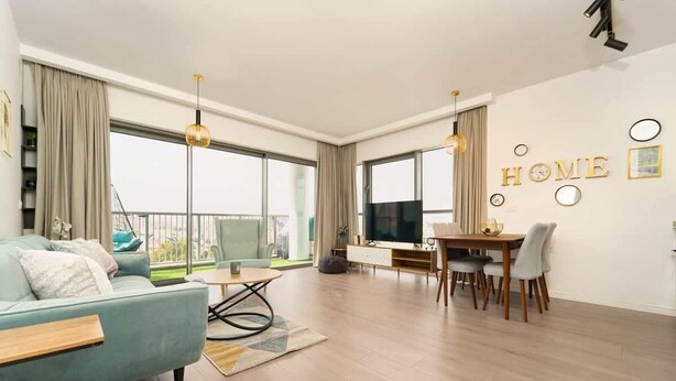 A modern living room with a sofa, coffee table, and dining area. - 1 Bedroom Savyon View - Isrentals (Jerusalem)