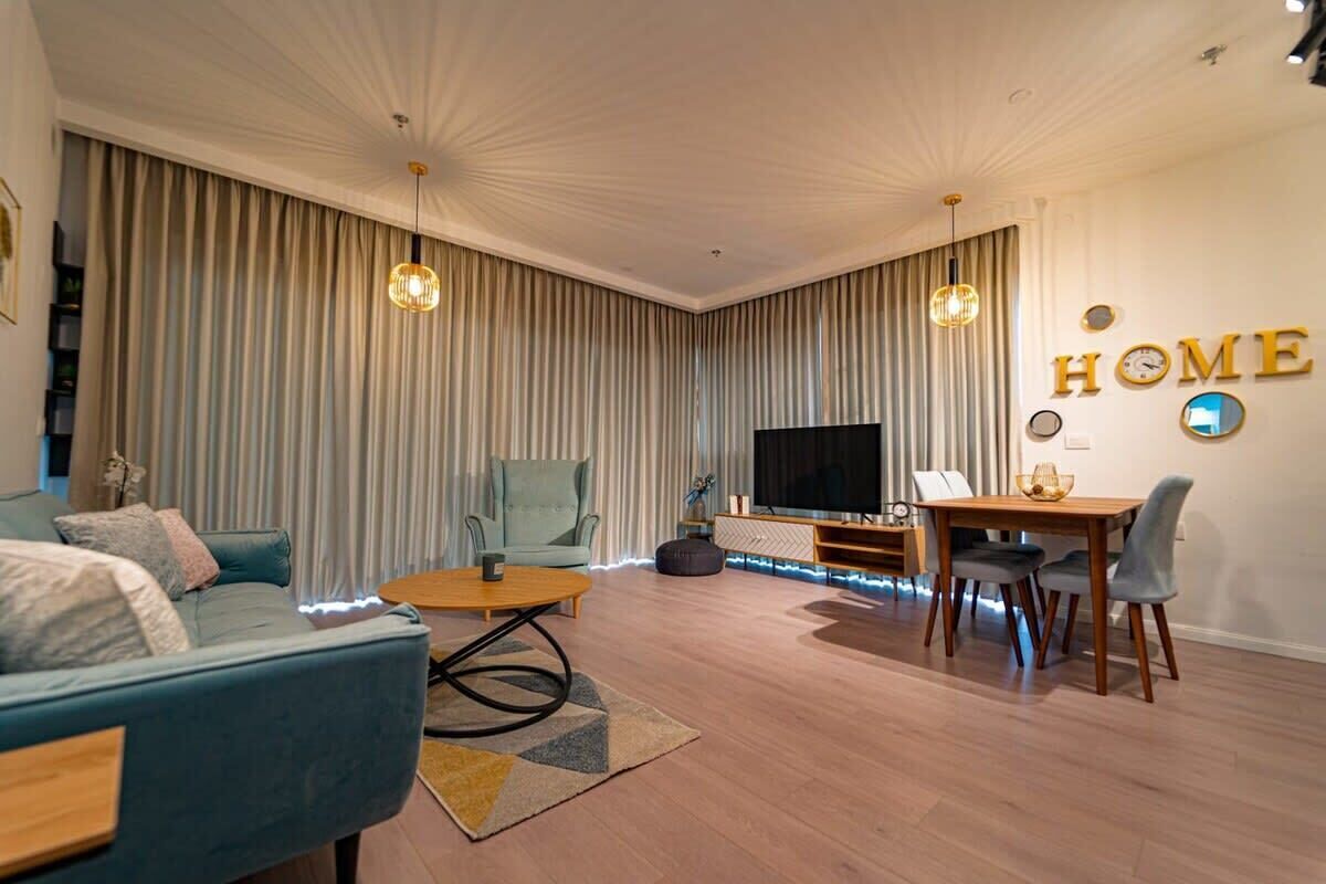 Una sala de estar moderna con un sofá, una mesa de centro, un televisor y un comedor con sillas y una mesa.
