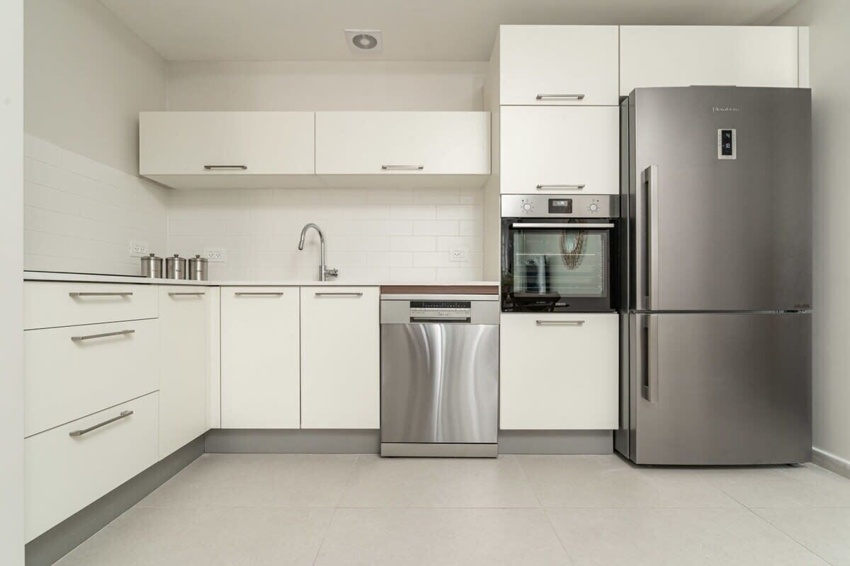 Una cocina moderna con armarios blancos, electrodomésticos de acero inoxidable y lavavajillas.