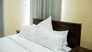 A neatly made bed with white linens and a wooden headboard in a hotel room. - The Backyard Lodge (Mpingu)