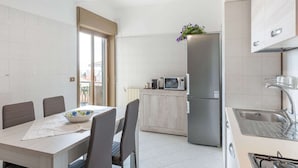 A modern kitchen with a dining area, a refrigerator, a microwave, and a stove.