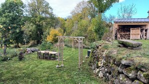A rustic outdoor setting with a wooden pergola, a table with chairs, and a stone wall. - Maison Restaurée: "lou Cantou des Randonneurs", Proche de Sentiers de Randonnées (chavagnac)