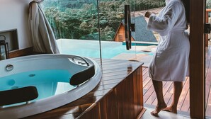 A person in a robe standing by a large window overlooking a mountainous landscape. - Chalés Laguna Alto Viçosa (Venda Nova Do Imigrante)