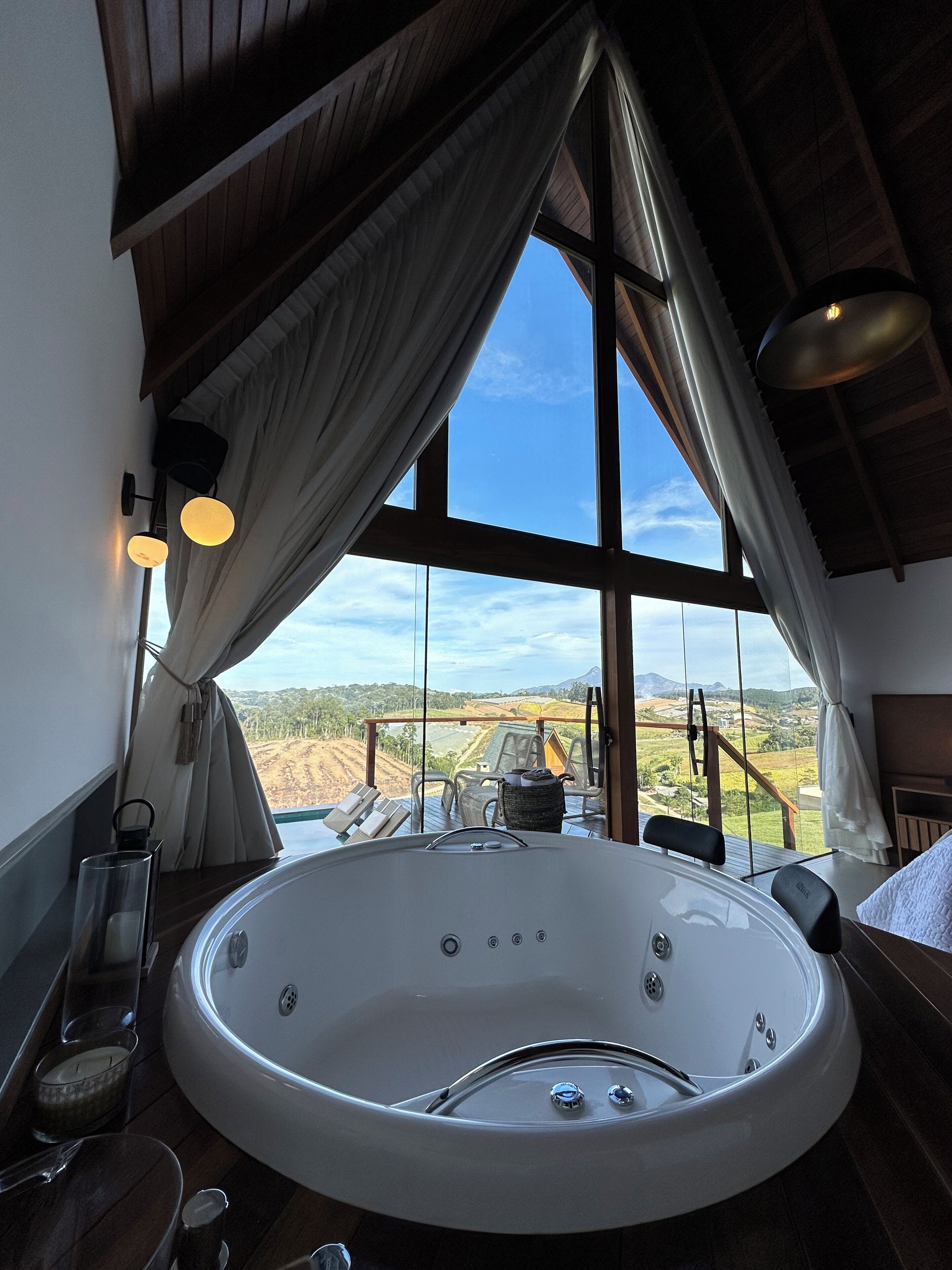 Un grand jacuzzi rond situé dans une pièce offrant une vue sur un paysage grâce à de grandes fenêtres.