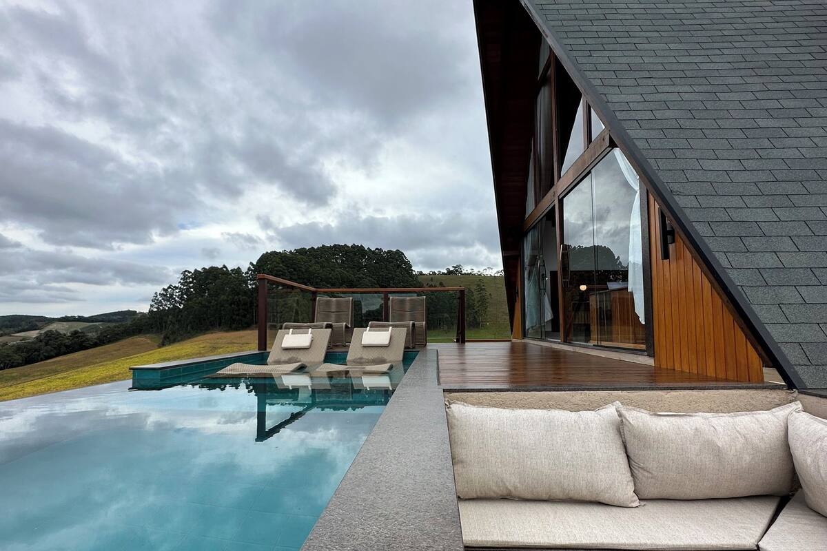 A modern outdoor pool area with lounge chairs and a wooden deck.