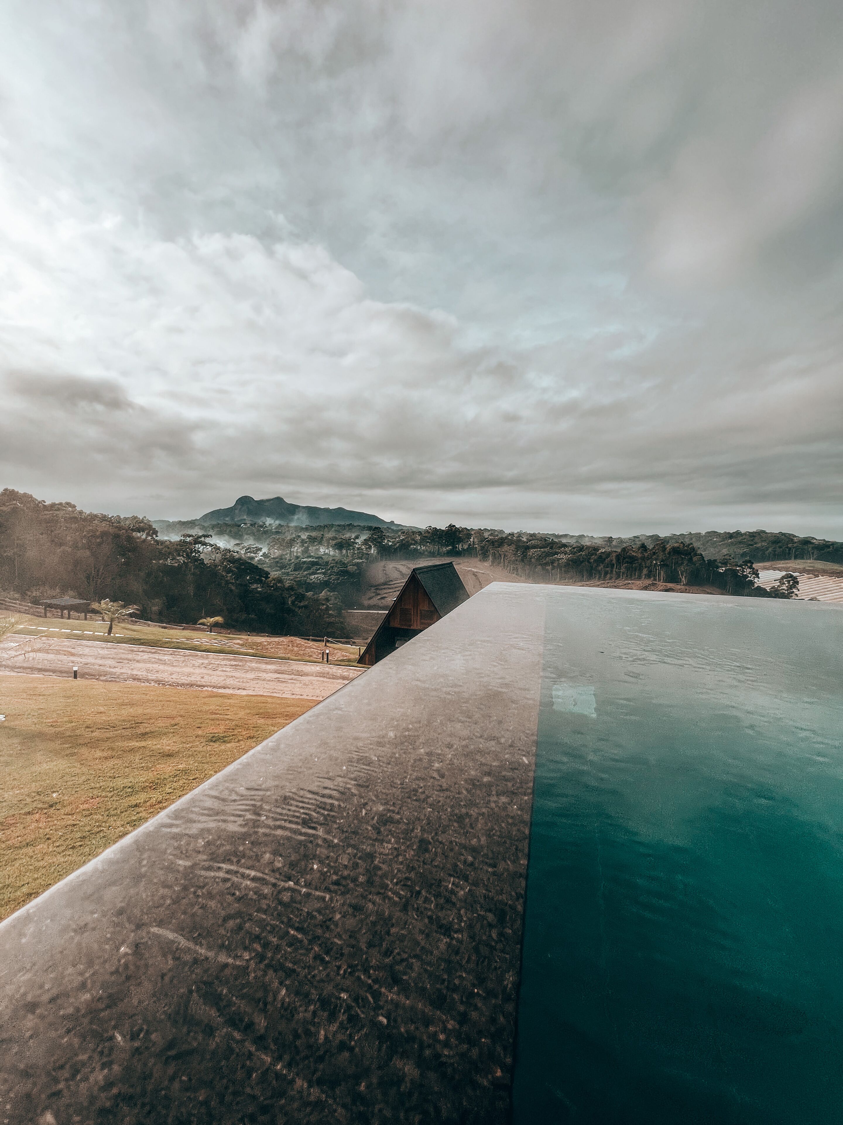 Une piscine offrant une vue sur un paysage vallonné, avec une structure en bois en arrière-plan.