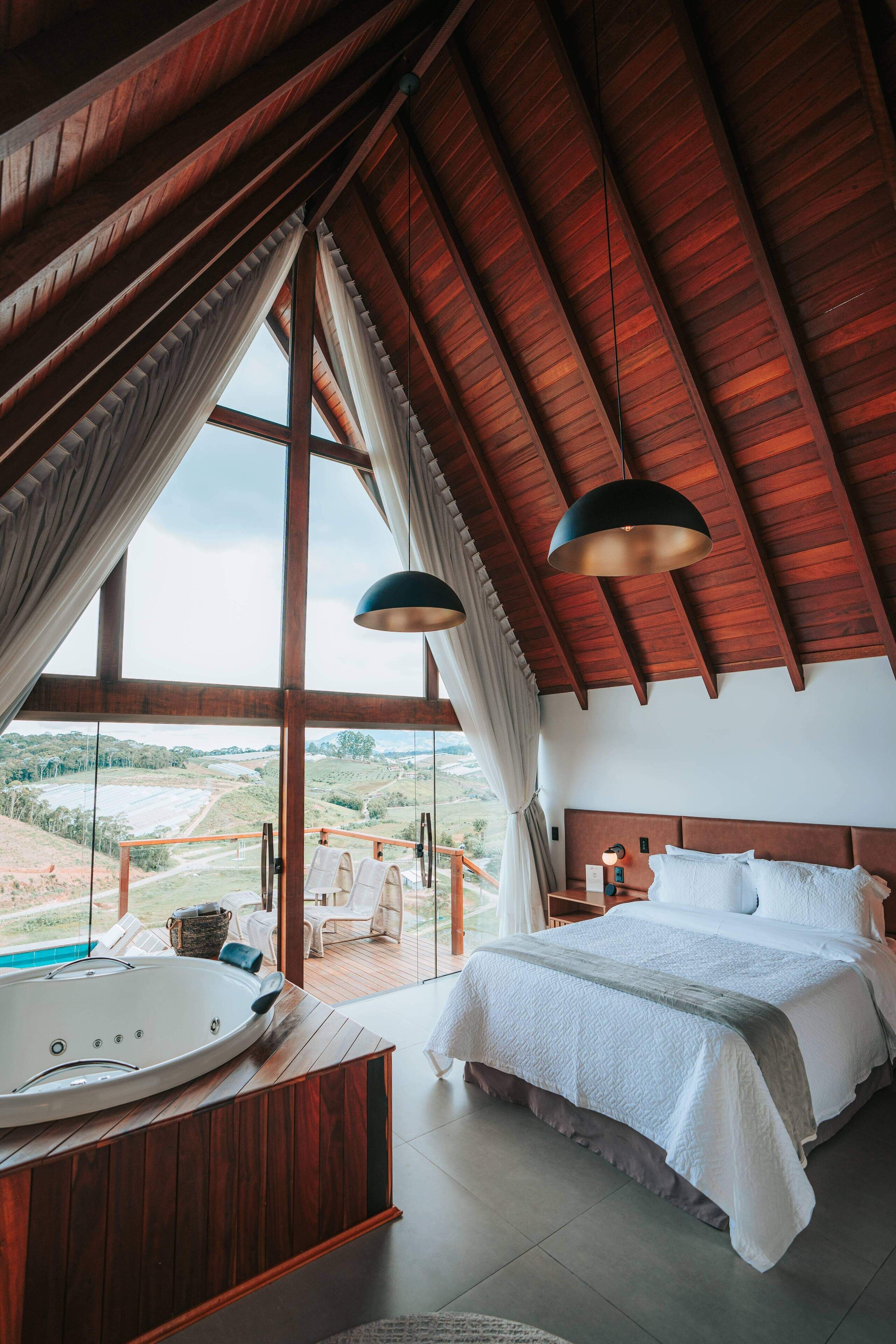 Un dormitorio con una cama grande, techo de madera y vistas a un paisaje.