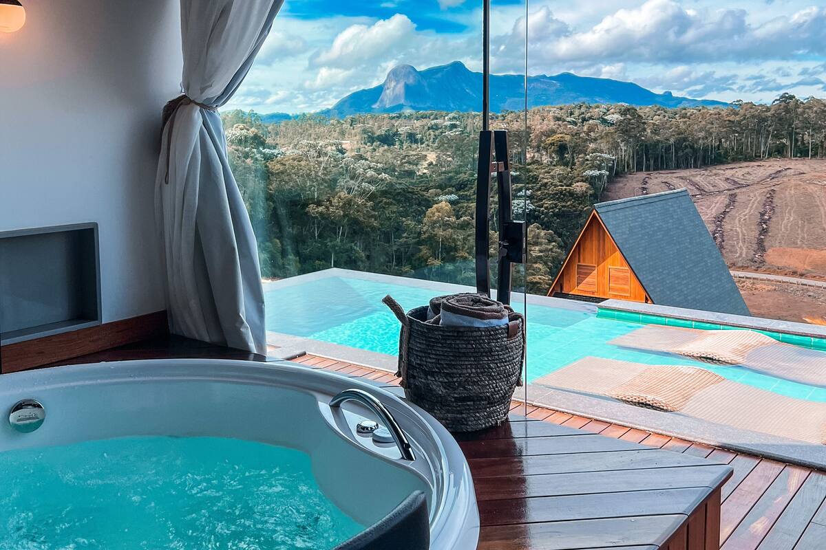 A hot tub on a wooden deck with a view of a mountain and forest.