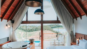A bedroom with a large window, wooden ceiling, and a bed with a white bedspread. - Chalés Laguna Alto Viçosa (Venda Nova Do Imigrante)