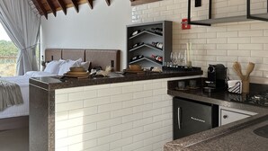 A modern kitchen with a central island, white tiled backsplash, and wooden ceiling beams. - Chalés Laguna Alto Viçosa (Venda Nova Do Imigrante)