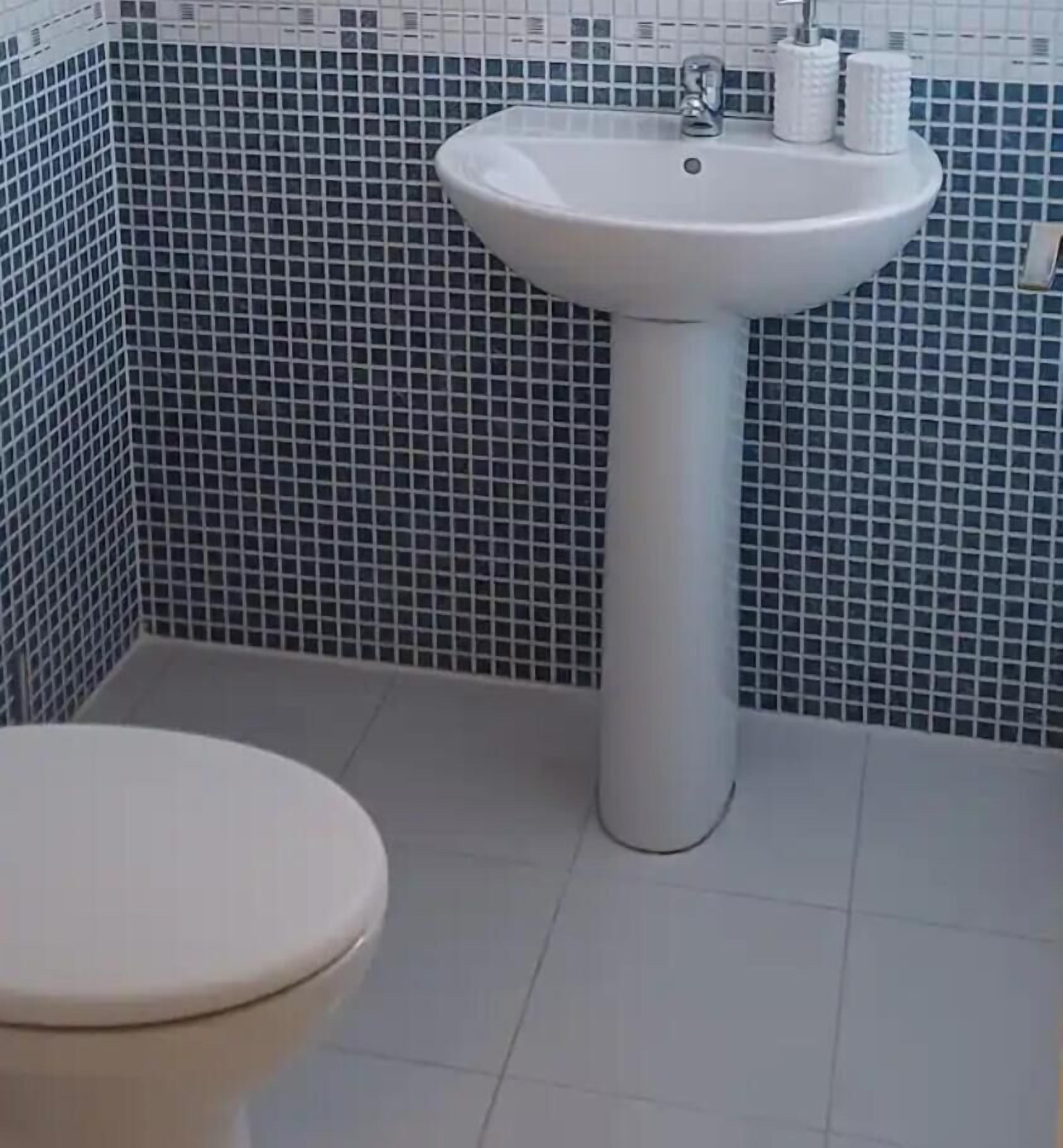 Een badkamer met toilet, wastafel en betegelde muren.