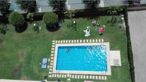 En vy från ovan av en swimmingpool omgiven av en välskött gräsmatta och träd.