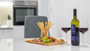 A table with a bottle of Plavag wine, two glasses of red wine, a wooden board with grapes, nuts, and cheese, and a glass of crackers. - Apartment in Imotski near Lakeside Bliss (imotski)