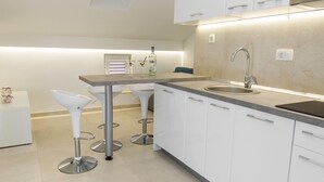 A modern kitchen with white cabinets, a stainless steel sink, and bar stools. - Apartment in Imotski near Lakeside Bliss (imotski)