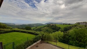 Ein Blick auf eine üppige, grüne Landschaft mit sanften Hügeln und einem Gebäude in der Ferne.