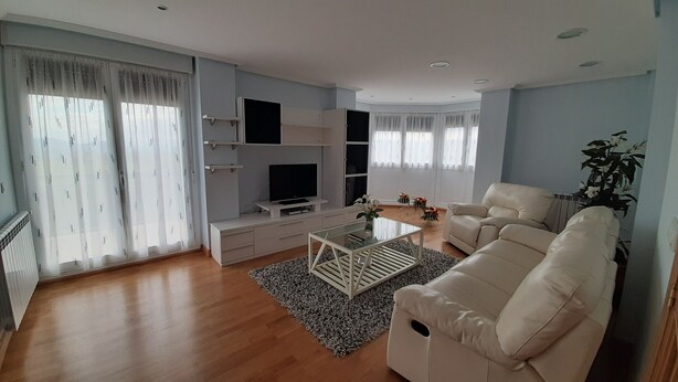 Ein modernes Wohnzimmer mit einer Couch, Fernseher und einem Couchtisch.