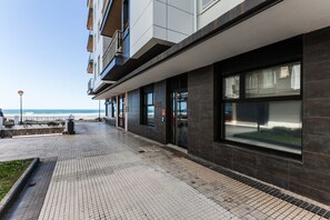 Ein modernes Gebäude mit großen Fenstern, einem gepflasterten Weg und Blick aufs Meer.