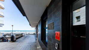 L’entrée d’un hôtel situé sur la côte, avec vue sur l’océan, un passage couvert et un clavier à code pour le contrôle d’accès.