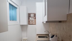 A compact kitchen with white cabinets, a countertop with a kettle, and a motivational quote on the wall. - Apartment Frida - Nice, 150m from the beach by Egona (Zarautz)