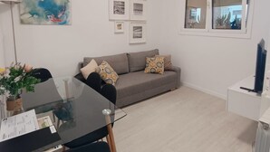 A modern living room with a glass dining table, grey sofa, and a painting of koi fish. - Apartment Frida - Nice, 150m from the beach by Egona (Zarautz)