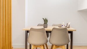 Een moderne eethoek met een houten tafel, twee stoelen en hanglampen.