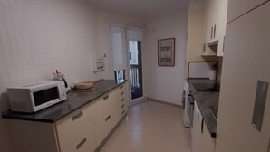 A kitchen with a microwave, cabinets, and a tiled floor. - Apartment Muskaria - Spectacular, first line beach and pool by Egona (Zarautz)