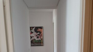 A narrow hallway with wooden flooring and white walls. There is a poster on the wall and a door on the left. - Apartment Muskaria - Spectacular, first line beach and pool by Egona (Zarautz)