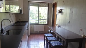 A compact kitchen with a window, a radiator, and a dining area with stools. - Zinkunegi Apartment - Accommodation near the beach with parking by Egona (Zarautz)