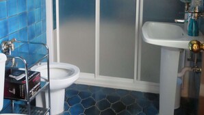 A bathroom with blue tiled walls, a white toilet, a shower enclosure, and a sink with a blue faucet. - Zinkunegi Apartment - Accommodation near the beach with parking by Egona (Zarautz)