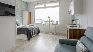 Une chambre moderne et bien éclairée, avec un lit, un bureau et une vue sur la mer.