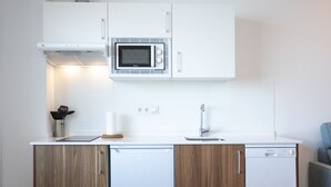 Une cuisine de taille réduite, équipée d’un four à micro-ondes, d’un évier et de meubles de rangement en bois.