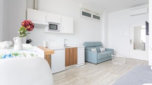 Un espace de vie moderne et compact comprenant un coin cuisine, un coin repas et un coin salon.
