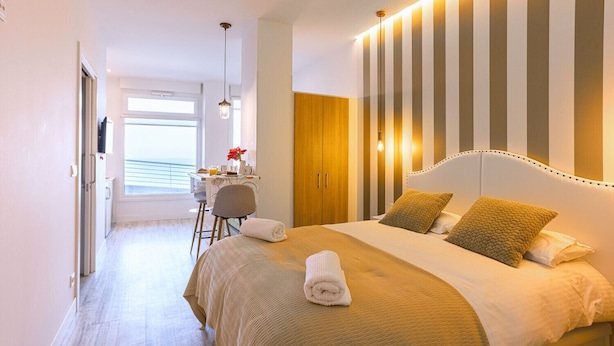 Ett hotellrum med en stor säng, ett skrivbord med en stol och utsikt över havet genom ett fönster.