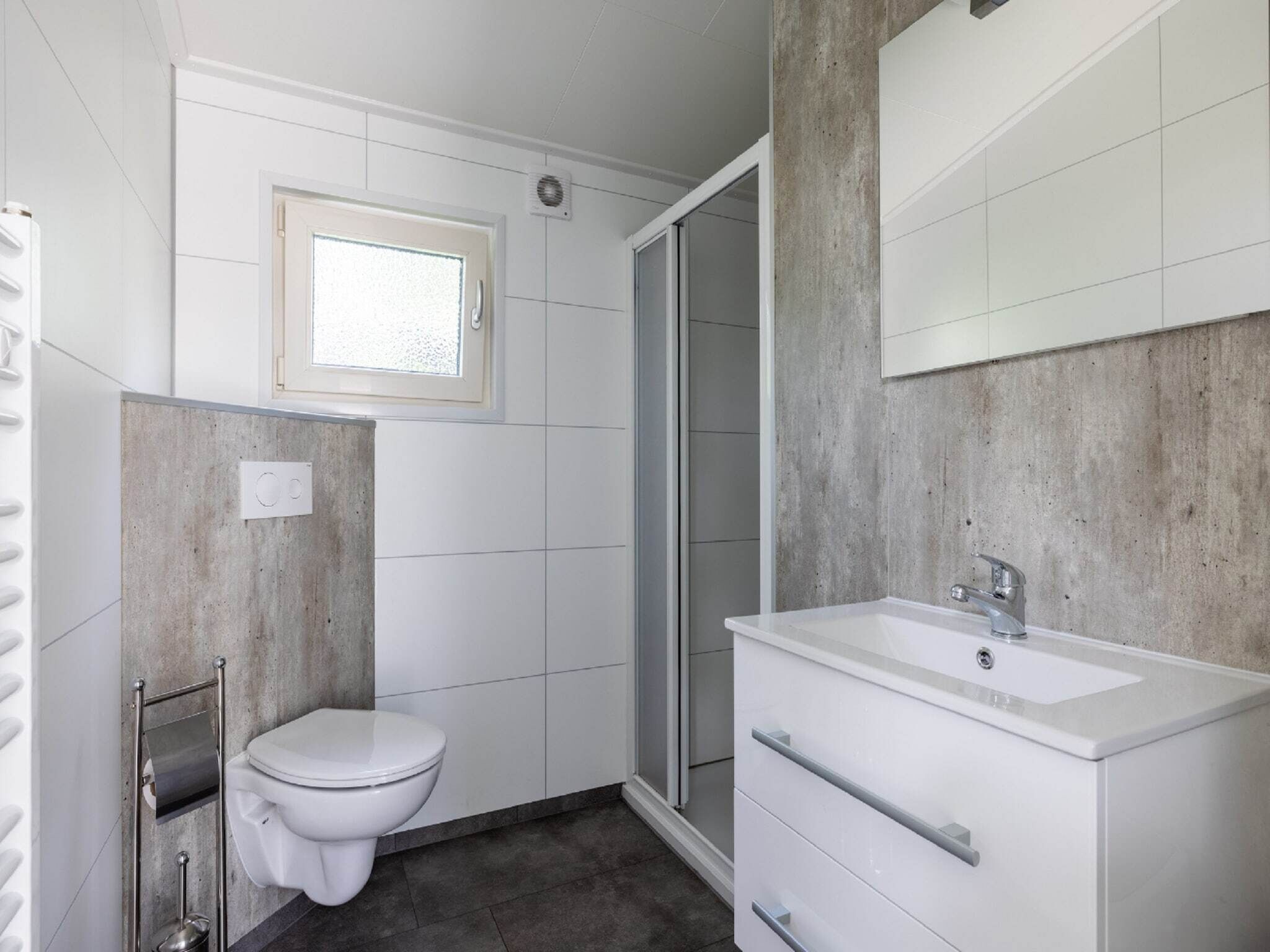 A modern bathroom with a toilet, a shower, and a sink.