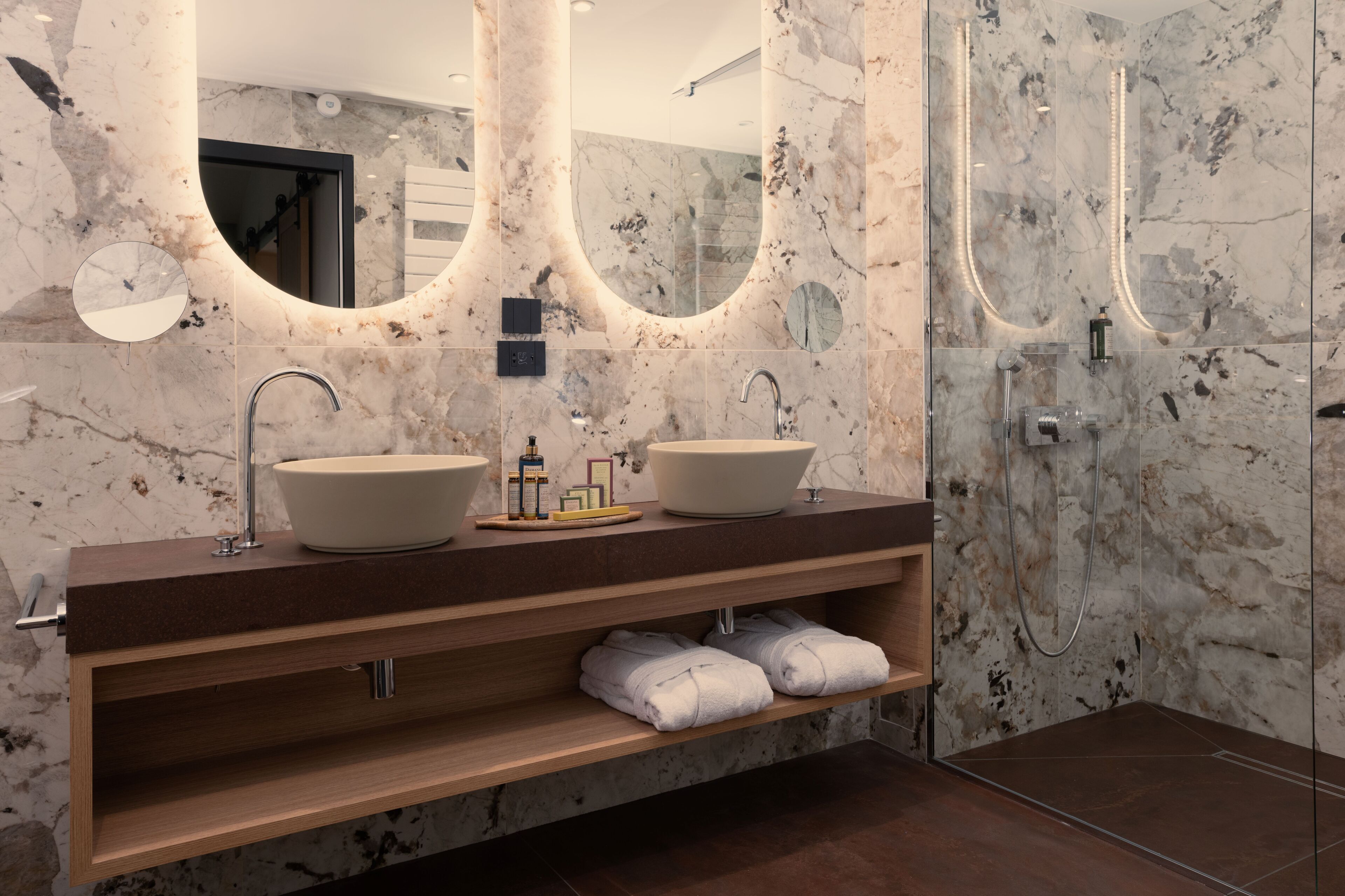 Un baño moderno con dos lavamanos, un espejo y una ducha.