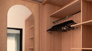 A modern walk-in closet with wooden shelving and a mirrored wardrobe.