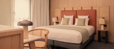 A hotel room with a bed, a desk, a chair, and two bedside tables with lamps.