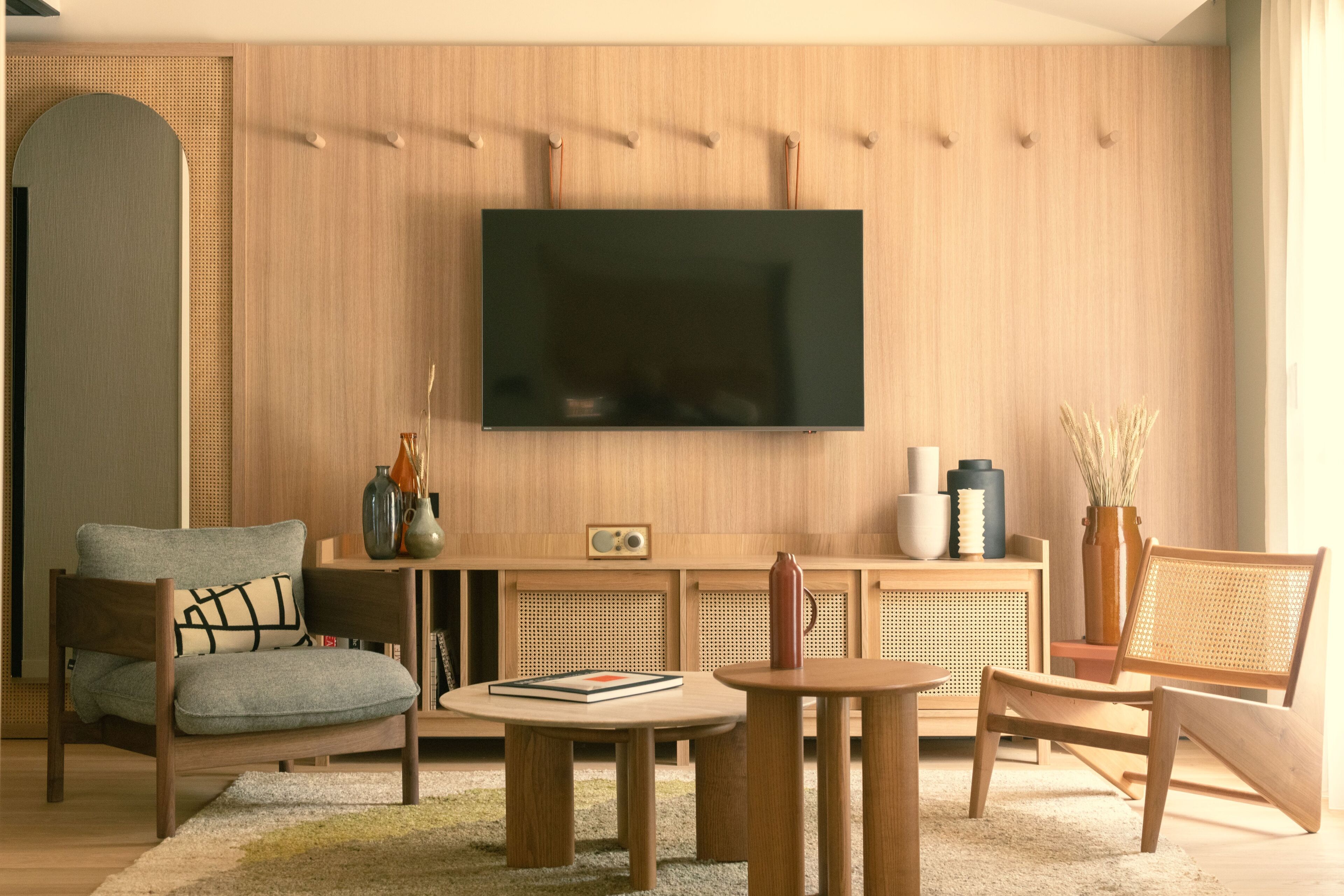 Un salon moderne doté d’un téléviseur à écran plat, de meubles en bois et d’un vase décoratif.