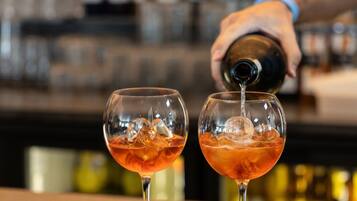 A bartender pouring a drink into two glasses.