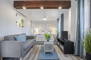 Relax in this stylish living room with a sofa, coffee table, and entertainment unit, featuring a comfortable bed and bedside lamps.